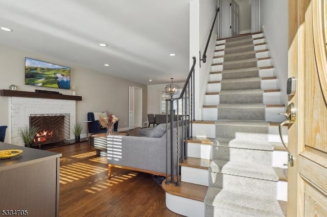 stairway featuring hardwood / wood-style floors, a fireplace, and a chandelier