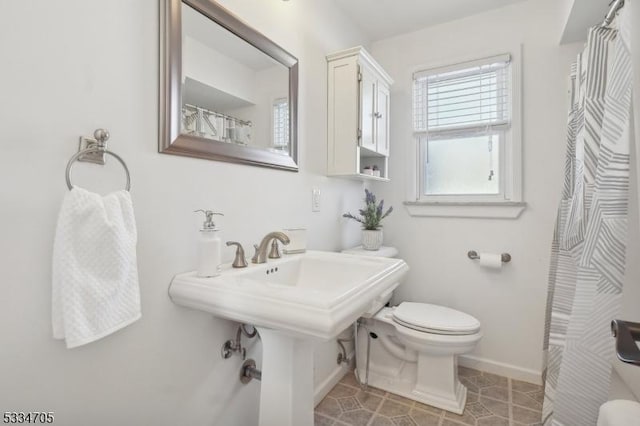 bathroom with a shower with curtain, sink, toilet, and tile patterned flooring