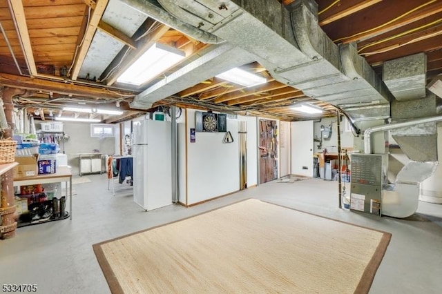 basement featuring heating unit and white refrigerator