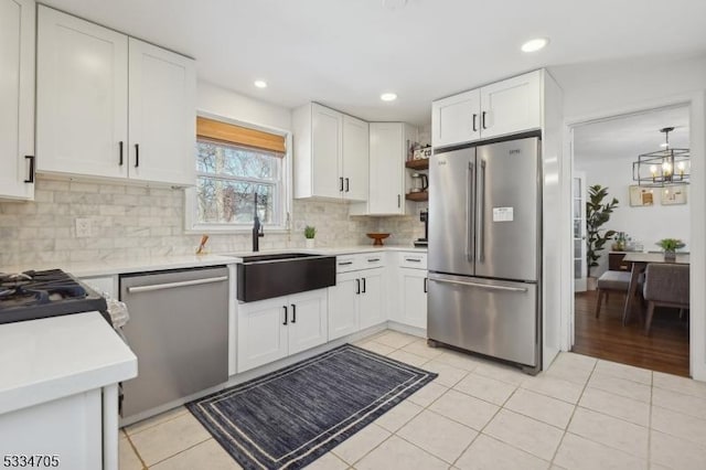 kitchen featuring light tile patterned flooring, white cabinetry, sink, decorative backsplash, and stainless steel appliances