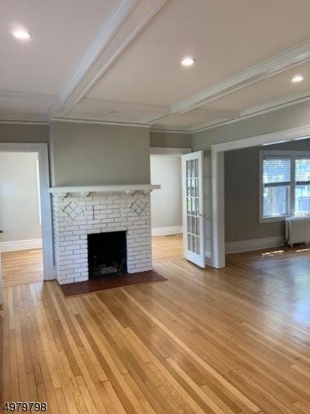 unfurnished living room featuring hardwood / wood-style floors, radiator heating unit, a fireplace, beamed ceiling, and crown molding