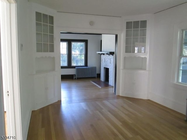 interior space featuring radiator, hardwood / wood-style flooring, and built in features