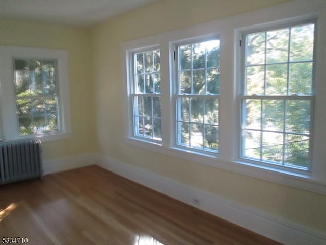 unfurnished room featuring radiator heating unit and hardwood / wood-style floors