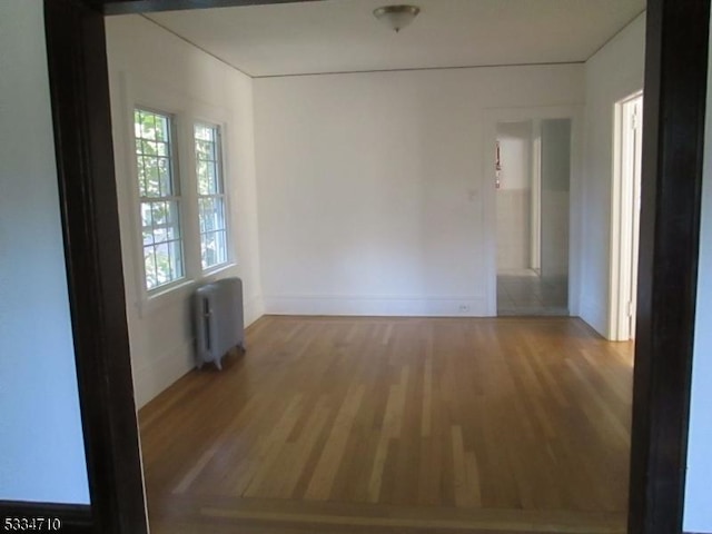 unfurnished room with radiator heating unit and wood-type flooring