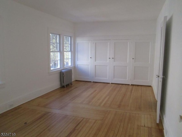 unfurnished bedroom featuring radiator and light hardwood / wood-style floors