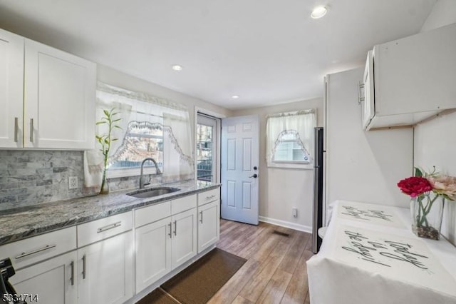 kitchen featuring white cabinetry, sink, decorative backsplash, and light hardwood / wood-style floors