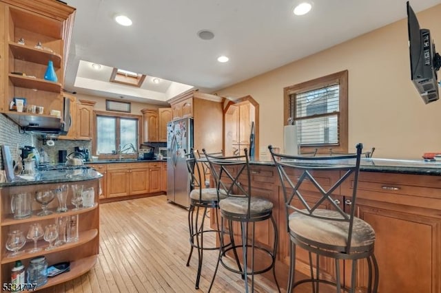 kitchen with plenty of natural light, stainless steel fridge, light hardwood / wood-style flooring, and backsplash