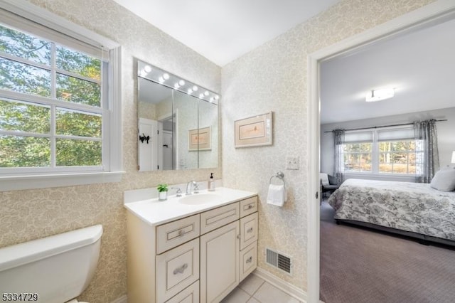 bathroom featuring tile patterned floors, vanity, toilet, and a wealth of natural light