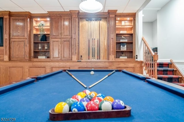 recreation room with pool table, built in features, and a drop ceiling