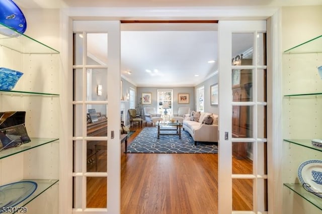 living room featuring french doors, ornamental molding, and hardwood / wood-style flooring