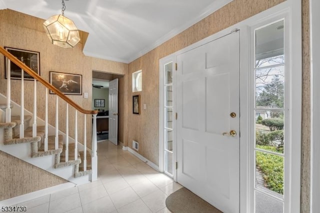 entryway featuring light tile patterned floors, crown molding, wallpapered walls, and stairs