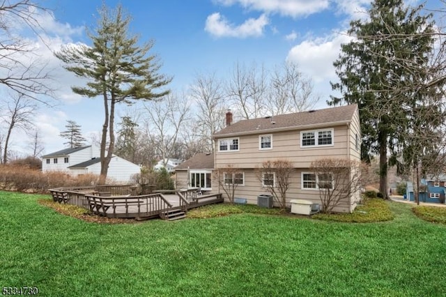 back of house featuring a yard, a wooden deck, a chimney, and central AC