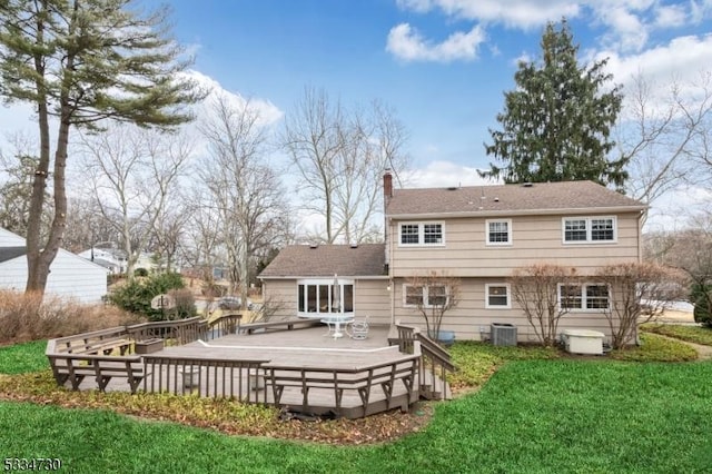 rear view of house with a chimney, a wooden deck, central AC, and a yard