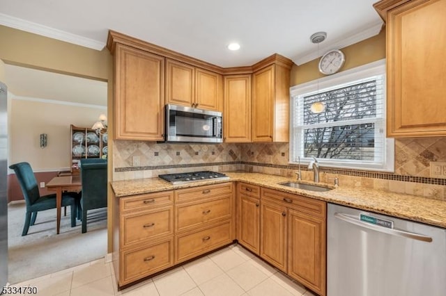 kitchen featuring crown molding, light stone countertops, appliances with stainless steel finishes, and a sink