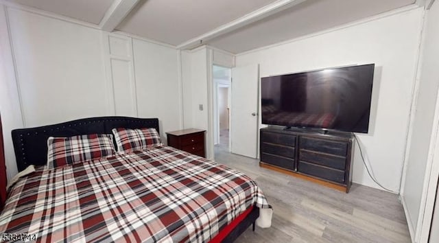 bedroom featuring light hardwood / wood-style flooring and beamed ceiling