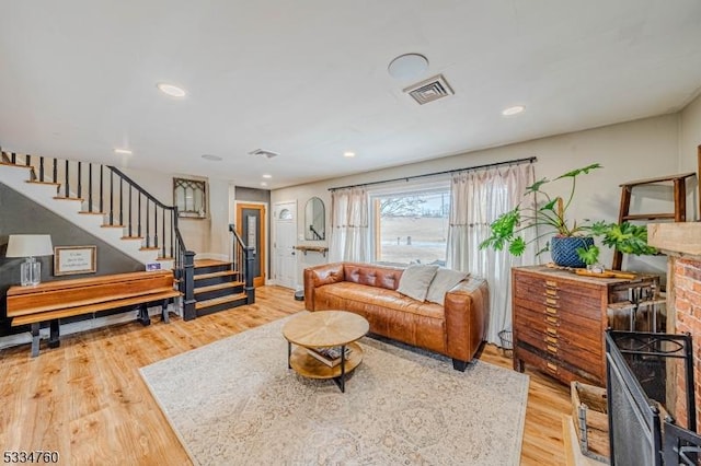 living room featuring a brick fireplace and light wood-type flooring