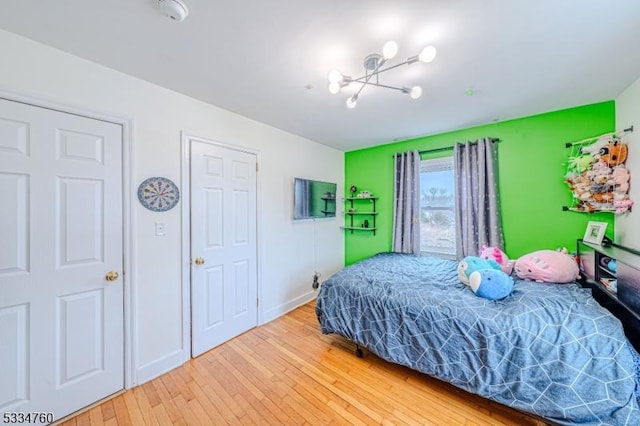 bedroom with wood-type flooring and a notable chandelier