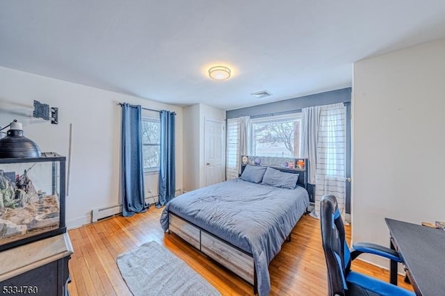 bedroom with wood-type flooring and a baseboard heating unit