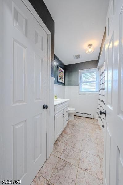 bathroom with a baseboard radiator, vanity, and toilet