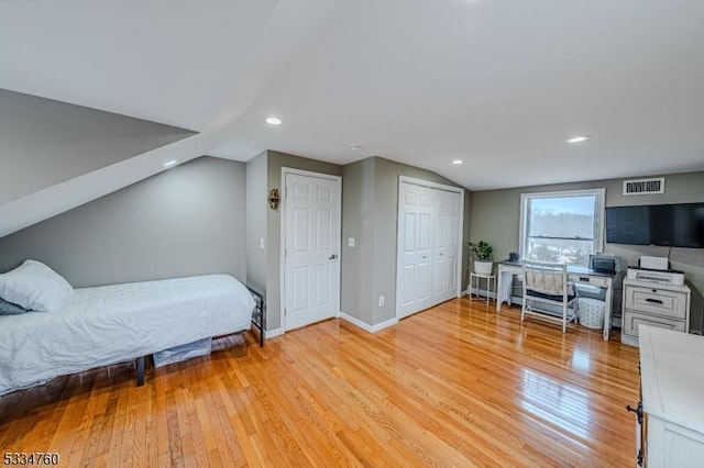 bedroom with lofted ceiling, a closet, and light wood-type flooring