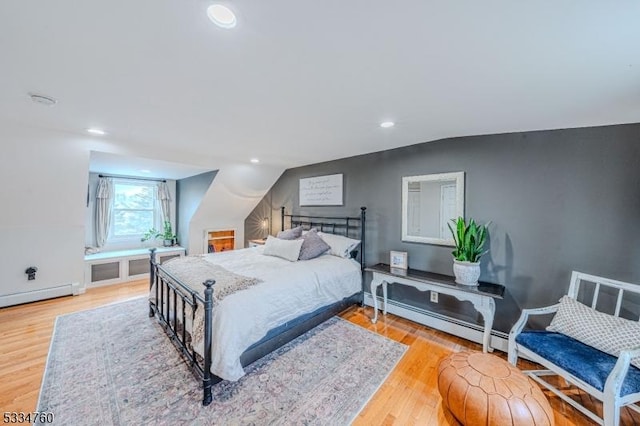 bedroom with lofted ceiling, light hardwood / wood-style floors, and baseboard heating