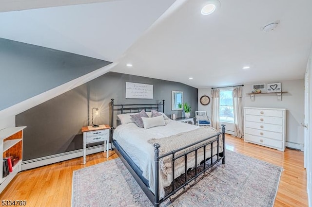 bedroom with vaulted ceiling, baseboard heating, and light hardwood / wood-style flooring