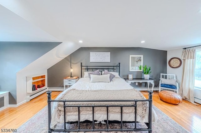 bedroom featuring lofted ceiling, a baseboard heating unit, and light hardwood / wood-style flooring