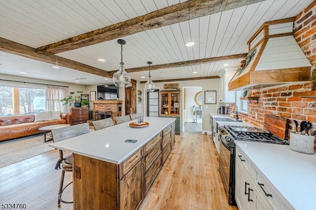 kitchen featuring a fireplace, white cabinets, hanging light fixtures, wood ceiling, and gas stove