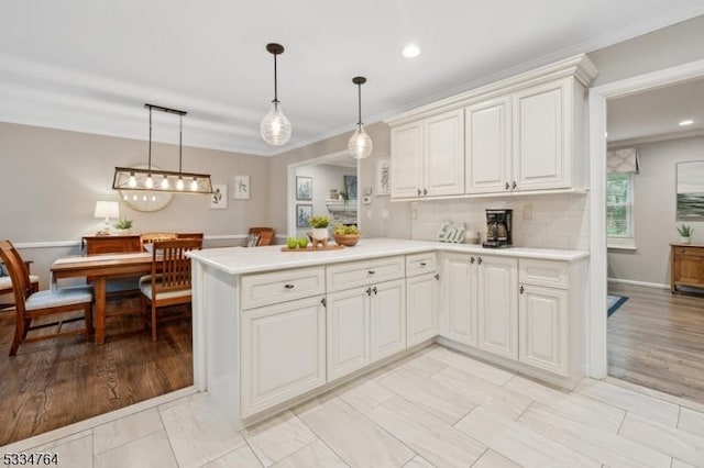 kitchen with light countertops, crown molding, decorative light fixtures, a peninsula, and recessed lighting