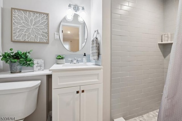 bathroom featuring toilet, vanity, and tiled shower