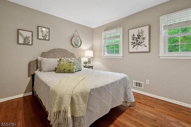 bedroom with baseboards, multiple windows, and wood finished floors
