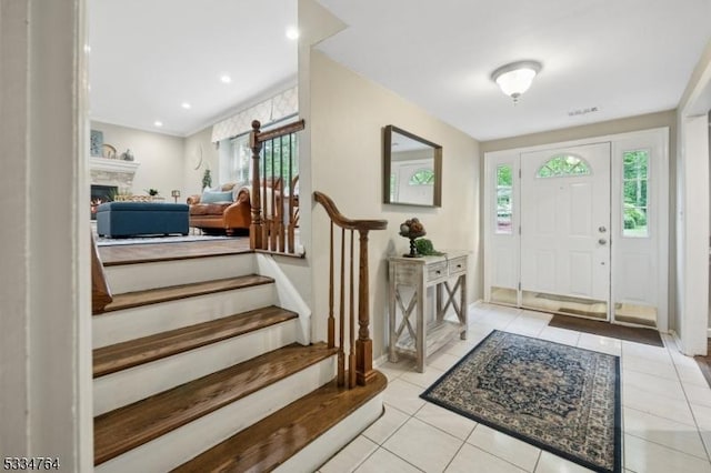 tiled entrance foyer featuring a warm lit fireplace and baseboards