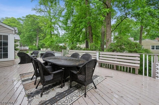 wooden terrace featuring outdoor dining area and view of wooded area