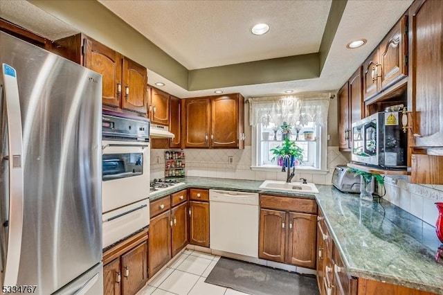 kitchen with sink, appliances with stainless steel finishes, tasteful backsplash, a textured ceiling, and light tile patterned flooring