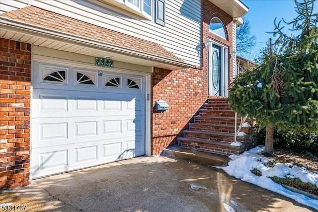 snow covered property entrance with a garage