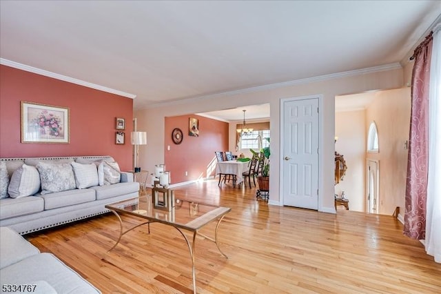 living room with crown molding, an inviting chandelier, and light hardwood / wood-style floors