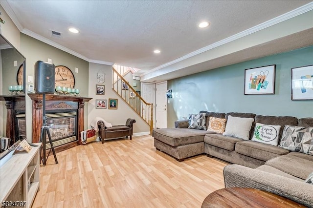 living room featuring ornamental molding, a textured ceiling, and light wood-type flooring