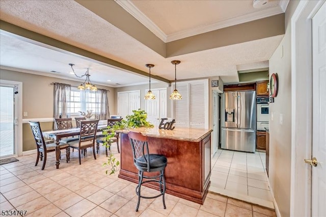 kitchen with ornamental molding, a breakfast bar area, light tile patterned floors, and stainless steel fridge with ice dispenser