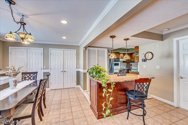 kitchen with ornamental molding, a breakfast bar, light tile patterned floors, and kitchen peninsula