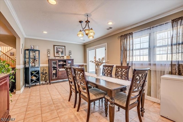 dining room with an inviting chandelier, crown molding, and light tile patterned flooring