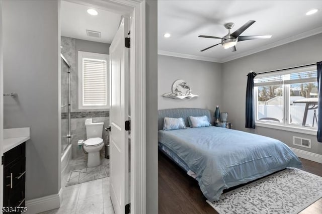 bedroom featuring ceiling fan, ensuite bath, and ornamental molding