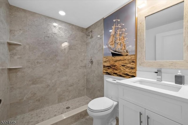 bathroom with vanity, tiled shower, and toilet