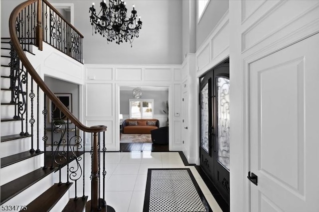 tiled foyer entrance featuring an inviting chandelier, french doors, and a high ceiling