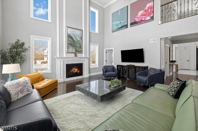 living room featuring ornamental molding, wood-type flooring, and a high ceiling