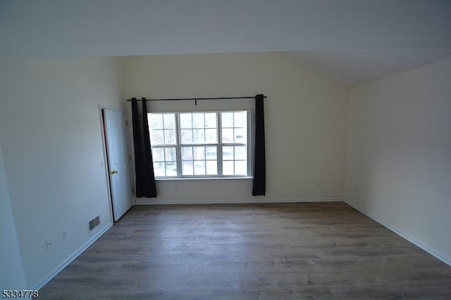 spare room with dark wood-type flooring and vaulted ceiling