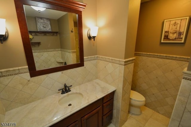 bathroom with tile patterned flooring, vanity, tile walls, and toilet