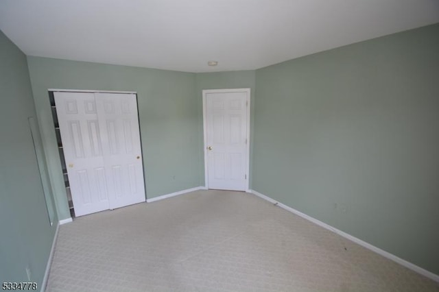 unfurnished bedroom with light colored carpet and a closet