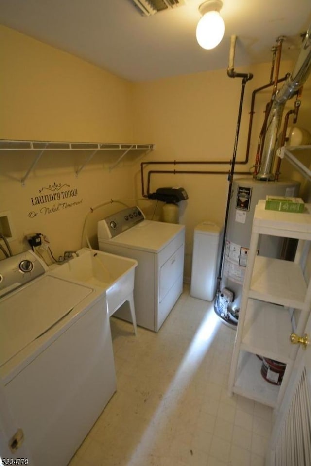 washroom with sink, gas water heater, and washing machine and clothes dryer