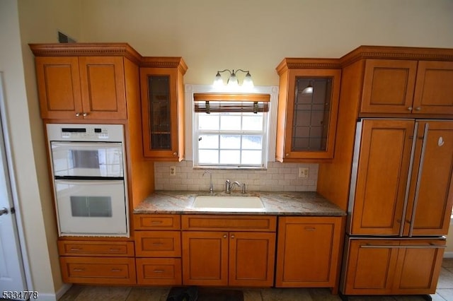 kitchen featuring sink, decorative backsplash, paneled built in fridge, and white double oven