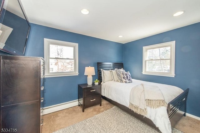 bedroom with multiple windows, a baseboard radiator, and light colored carpet